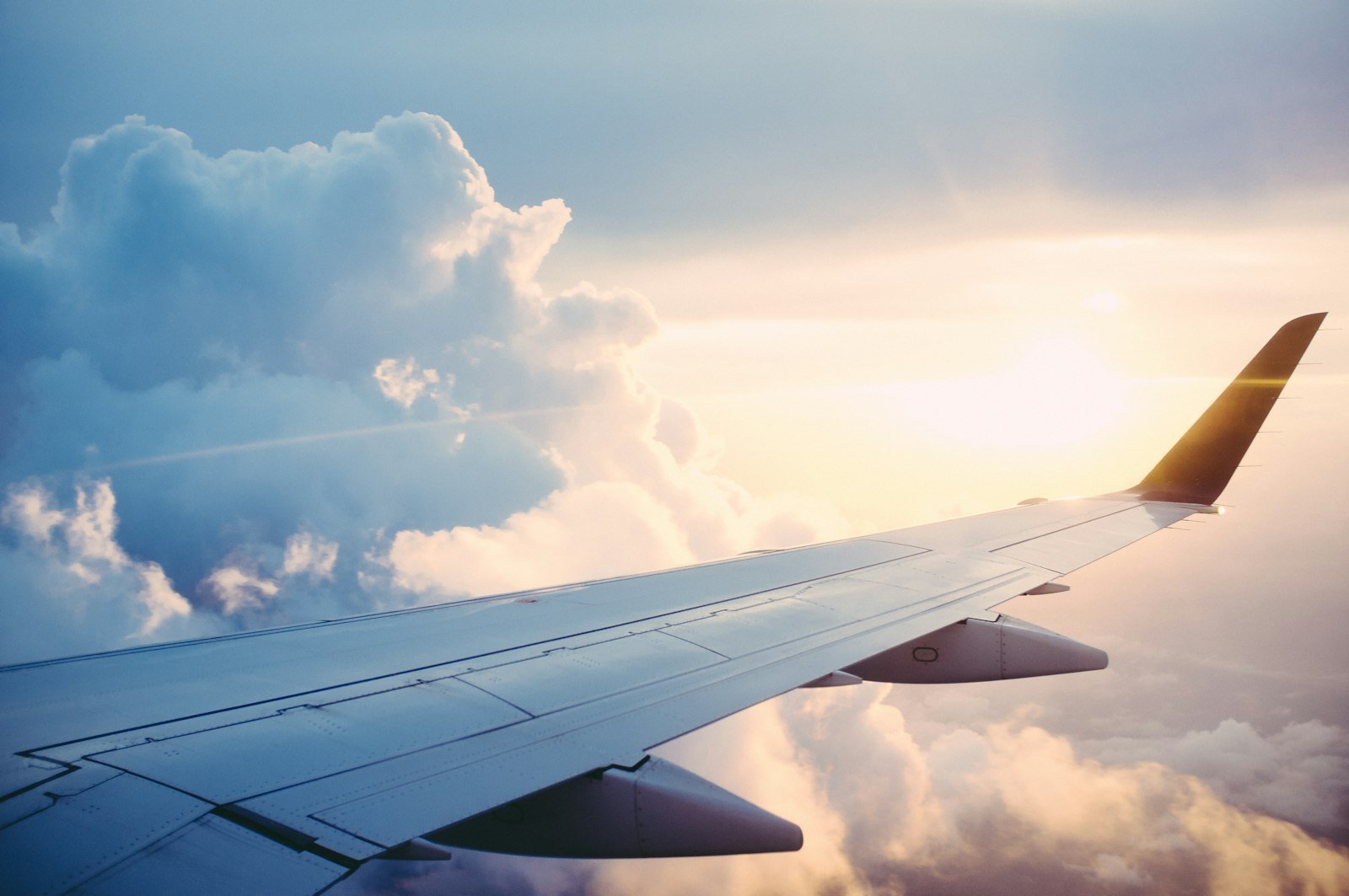 Ala de un avión sobre nubes al atardecer, vista desde la ventanilla